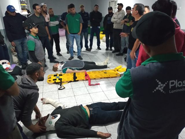 Simulação de resgate: vítimas deitadas no chão e em maca, cercadas pelos brigadistas em treinamento.